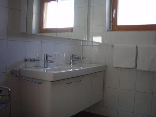 La salle de bains blanche est pourvue d'un lavabo et d'une fenêtre. dans l'établissement Top Appartements, à Brand