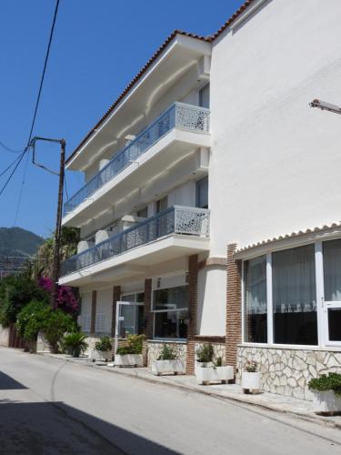 a white building with potted plants on a street at Panorama Hotel - Restaurant in Diakopto