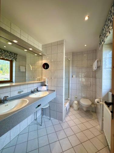 a large bathroom with two sinks and a toilet at Hotel Bergland in Grainau