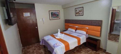 a small bedroom with a bed and a television at Aruba Suite Hotel in Lima