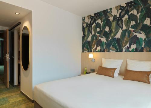 a bedroom with a white bed with a painting on the wall at Le Côté Vert in Waterloo