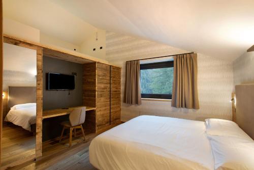 a hotel room with a bed and a desk and a television at Valgrisa Mountain Lodges 1 in Valgrisenche