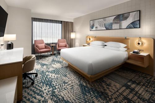 デルタにあるDelta Hotels by Marriott Vancouver Deltaの大きなベッドと椅子2脚が備わるホテルルームです。