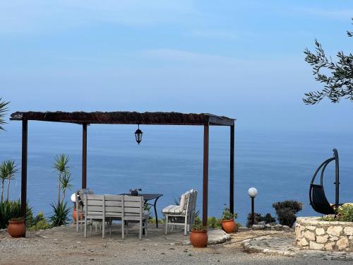 a table and chairs under a gazebo with the ocean at La Casa D' Irene in Agios Nikitas