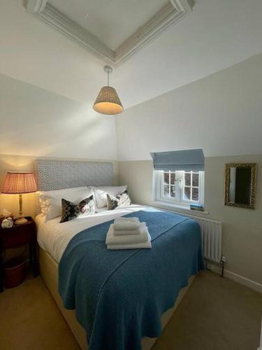 a bedroom with a blue bed with towels on it at Northbrook Cottage, Farnham, up to 8 adults in Farnham