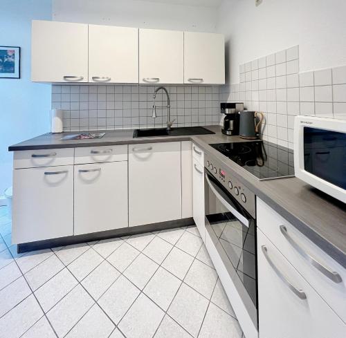 eine Küche mit weißen Schränken und einer Mikrowelle in der Unterkunft Atelierwohnung mit Parkblick in Erfurt