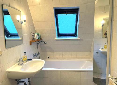 ein Badezimmer mit einem Waschbecken, einer Badewanne und einem Spiegel in der Unterkunft Atelierwohnung mit Parkblick in Erfurt