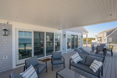 a screened porch with chairs and tables and the ocean at 114 Salt Marsh Road East Sandwich Seaglass in East Sandwich