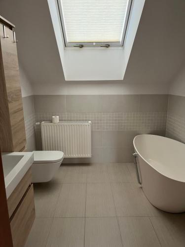 a bathroom with a tub and a sink and a skylight at Dom nad Zalewem Zegrzyńskim in Nieporęt