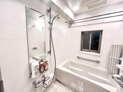 Baño blanco con bañera y lavamanos en Shibuya Harajuku big house, en Tokio