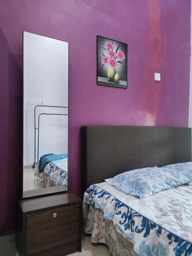 a bedroom with purple walls and a bed and a mirror at NikNa Homestay Batu Rakit - WIFI in Kampong Ru Tujoh