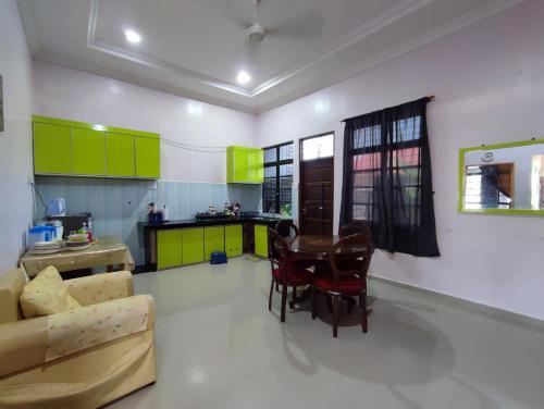 a living room with green cabinets and a table and chairs at NikNa Homestay Batu Rakit - WIFI in Kampong Ru Tujoh