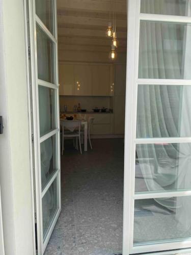 a room with two glass doors and a kitchen at La casa di Giò: piccolo gioiello in centro Como in Como