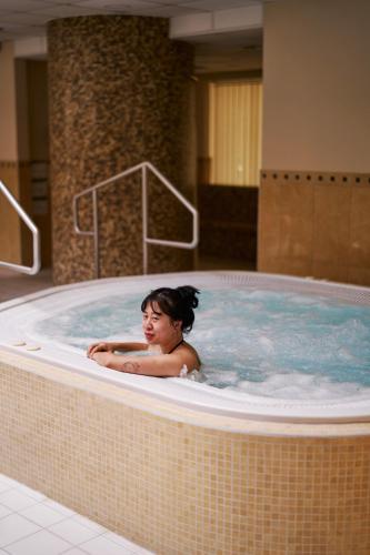 a woman is sitting in a hot tub at Jantar Hotel & SPA by Zdrojowa in Kołobrzeg