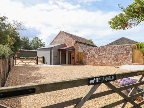 a barn conversion with a gate in front of a house at Bumblebee Cottage in Wellington