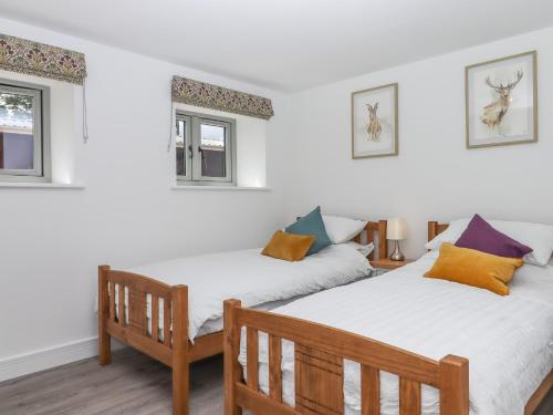 two beds in a room with two windows at Bumblebee Cottage in Wellington