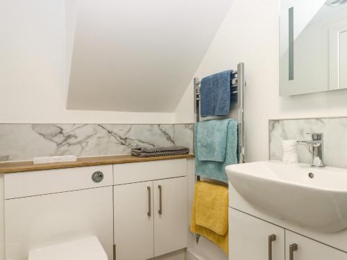 a white bathroom with a sink and a mirror at Bumblebee Cottage in Wellington