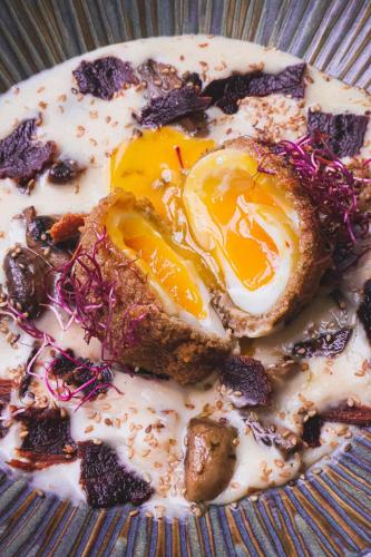 a fried egg on a plate on a table at Hôtel & Restaurant des Remparts in Rochefort