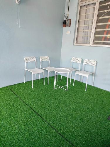 a group of chairs and a table with green grass at MunadibStay Private Pool in Ketereh