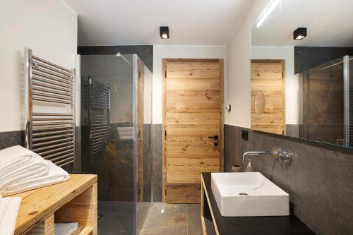 ein Badezimmer mit einem weißen Waschbecken und einer Dusche in der Unterkunft Valgrisa Mountain Lodges 2 in Valgrisenche