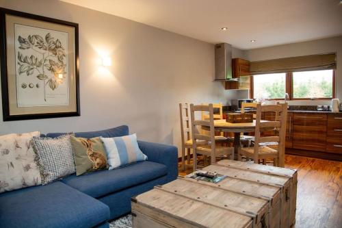 a living room with a blue couch and a table at Azalea Northbrook Park Chalet in Farnham