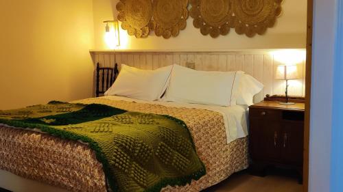 ein Bett mit weißen Kissen und einer grünen Decke in der Unterkunft CS50 Alojamiento 1 dormitorio Monforte de Lemos in Monforte de Lemos