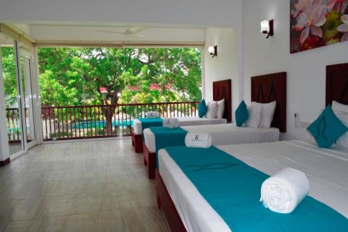 two beds in a room with a balcony at Anantamaa Hotel in Trincomalee