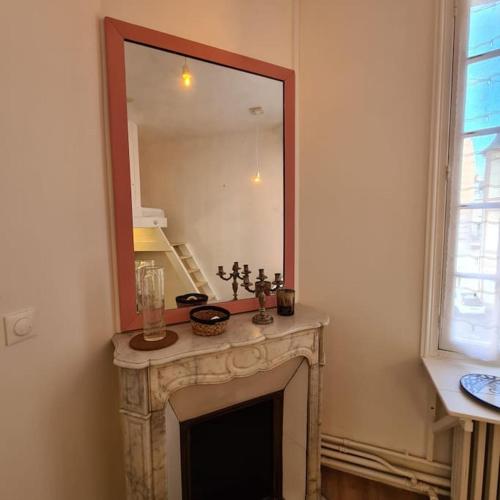 - un salon avec une cheminée et un grand miroir dans l'établissement Beau studio à 30m de la plage / Beautiful studio 30m from the beach, à Trouville-sur-Mer