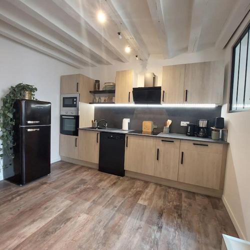 une cuisine avec un réfrigérateur noir et des armoires en bois dans l'établissement La Maison du 19 - 130m2 - Les Rosiers sur Loire - Chambres climatisées, à Les Rosiers