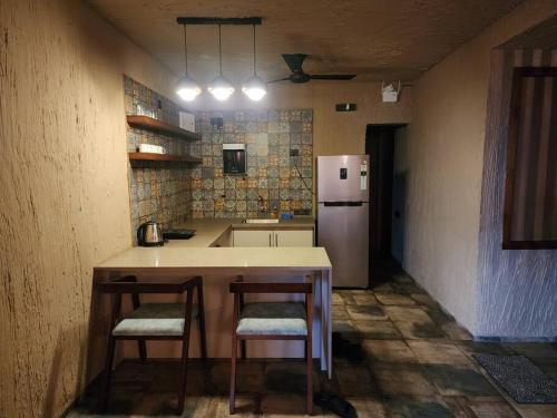 a kitchen with a table and two chairs and a refrigerator at Revanta Studio Flat in Kolhapur
