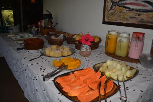 a table topped with plates of fruit and other foods at Pousada Watu Kerere in Praia do Rosa
