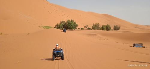 een man op een motor in de woestijn bij Merzouga Chebbi camp in Adrouine