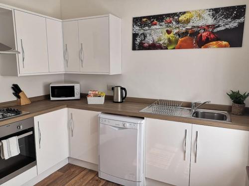 a kitchen with white cabinets and a sink at Estuary View, Bank House, Stunning apartment. in Millom