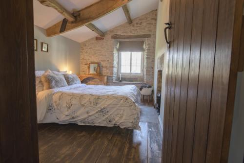 a bedroom with a bed and a brick wall at Pond Cottage in West Witton