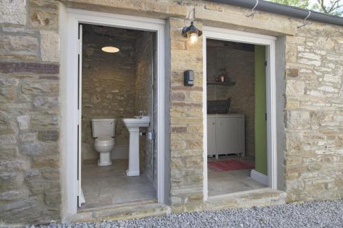 a stone bathroom with a toilet and a sink at Pond Cottage in West Witton