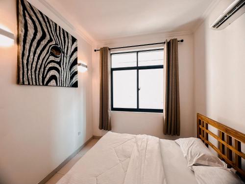 1 dormitorio con 1 cama y una foto de cebra en la pared en Elles Residence, en Dar es Salaam