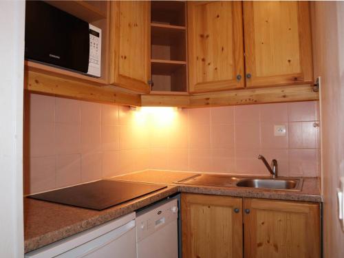La cuisine est équipée de placards en bois, d'un évier et d'un four micro-ondes. dans l'établissement Charmant T2, Accès Piscine, Sauna, Ski-In/Out, Balcon Ouest, 6 Pers - Les Orres 1800 - FR-1-322-343, aux Orres