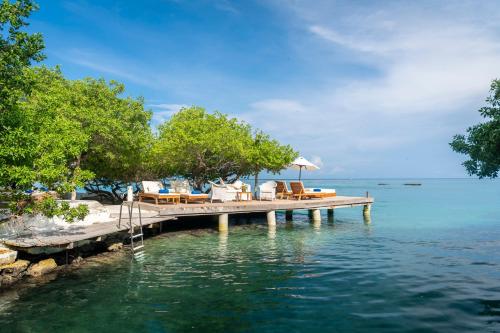 eine Anlegestelle mit Stühlen und Sonnenschirmen auf dem Wasser in der Unterkunft Hotel Coralina Island in Isla Grande