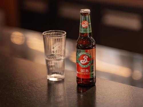 a bottle of beer next to a glass on a table at Ibis Paris Gare Montparnasse Catalogne in Paris