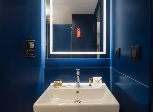 een blauwe badkamer met een witte wastafel en een spiegel bij Ibis Paris Gare Montparnasse Catalogne in Parijs