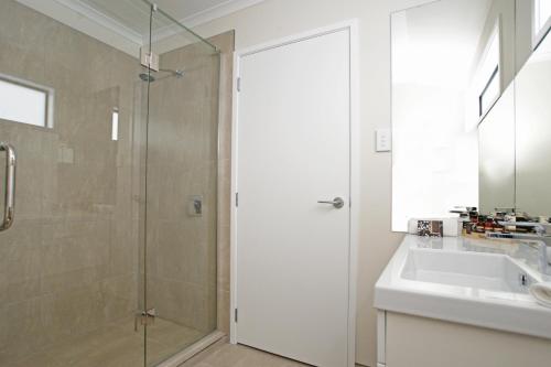 a bathroom with a shower and a sink and a mirror at Astra Motor Lodge in Hamilton