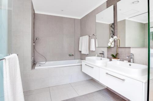 a bathroom with two sinks and a tub and a shower at Urban Oasis Apartments at Masingita Towers in Johannesburg