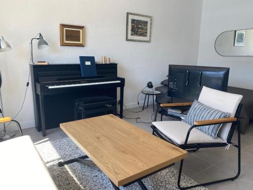 een woonkamer met een piano, een tafel en een stoel bij Cassis Appartement bord de mer, vue exceptionnelle in Cassis