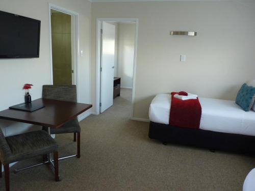 a hotel room with a bed and a table and a desk at Astra Motor Lodge in Hamilton
