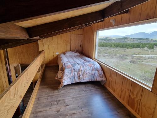 Bett in einem Zimmer mit einem großen Fenster in der Unterkunft Descanso garantizado Cochrane in Cochrane