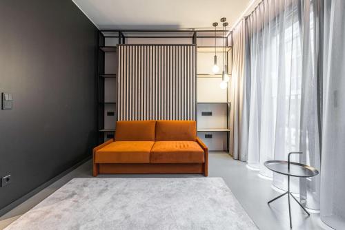 an orange couch in a room with a window at YUMA Apartments Leipzig Berliner Straße in Leipzig