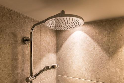 a shower with a shower head in a bathroom at YUMA Apartments Leipzig Berliner Straße in Leipzig