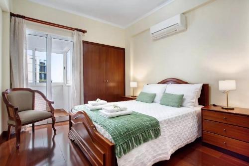 a bedroom with a bed with a chair and a window at Central Living Funchal in Funchal