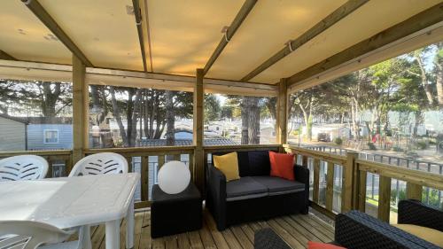 - une terrasse couverte avec un canapé, une table et des chaises dans l'établissement Mobil home 3 chambres 40 m2, à Quiberon