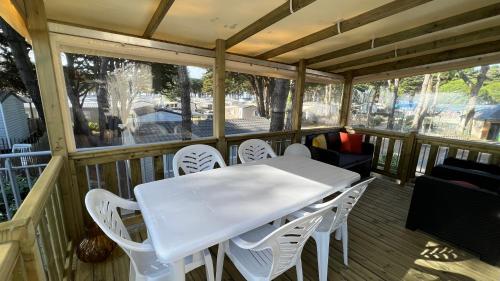 - une table et des chaises blanches sur une terrasse couverte dans l'établissement Mobil home 3 chambres 40 m2, à Quiberon